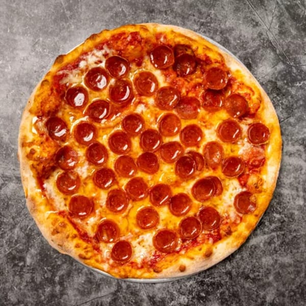 A freshly baked pepperoni pizza with melted cheese and a golden crust on a dark surface.