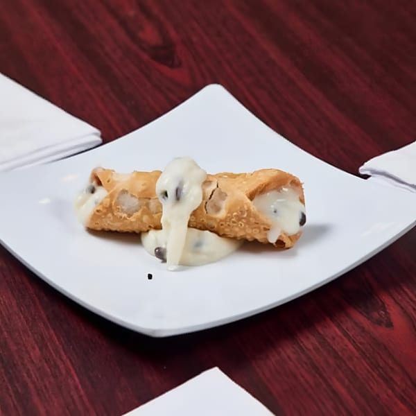 Two cannolis with creamy white filling and chocolate chips on a white plate.