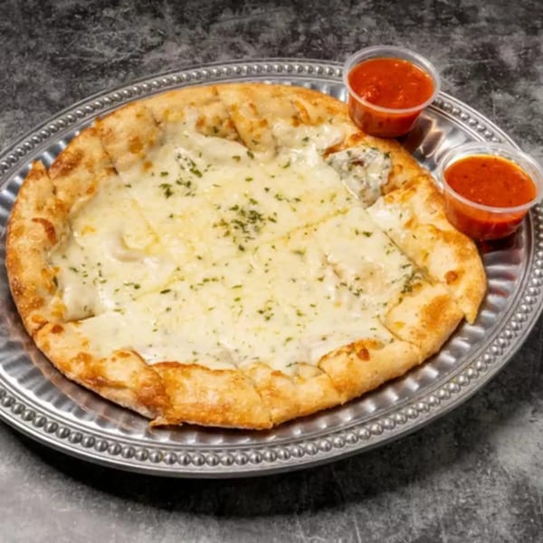 Cheesy garlic bread with two small cups of marinara sauce on a silver platter.
